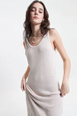 Vestido largo de punto color beige, con textura acanalada y escote redondo. De tiras finas y silueta al cuerpo, con tajo lateral.