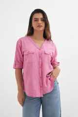 Camisa rosa de algodón con escote en V, mangas 3/4 con trabilla y botón, cierre frontal con botones y dos bolsillos de parche en el pecho.