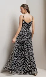 Vestido largo de fiesta negro con breteles finos y escote en V. El vestido es de tul bordado con flores y lentejuelas plateadas.