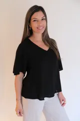 Blusa negra de tela liviana con escote en V y mangas cortas con volados.