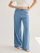 Pantalón gris de tiro medio alto, corte ancho, con bolsillos delanteros y traseros, detalles de atraques y triples costuras en color amarillo.