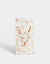 Collar corto dorado con doble cadena, una de eslabones y otra con cuentas y perlas. Incluye dijes de corazones y flores encapsuladas.