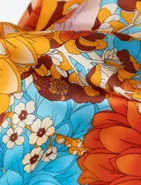 Pañuelo cuadrado de satén estampado con diseño floral en tonos naranja, celeste y lila.