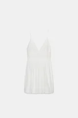 Vestido corto blanco con escote en pico y tirantes finos. Detalle de bordados combinados a tono en el escote y el ruedo.