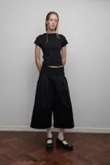 Bermuda sastrera negra confeccionada en felpa con pretina de lycra de algodón, tiro bajo, bolsillos laterales y pliegue delantero de gran tamaño.