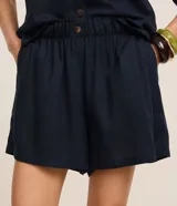 Short blanco de corte runner evasé, con cintura elástica fruncida y un botón decorativo. Presenta bolsillos laterales y un calce suelto.