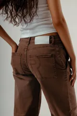 Pantalón de denim color marrón oscuro, tiro medio, con silueta wide leg y costuras verticales marcadas en el frente de ambas piernas.