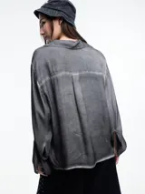 Camisa gris de manga larga confeccionada en viscosa teñida en frío, con efecto gastado. De corte relajado, con bolsillo delantero y puños amplios.