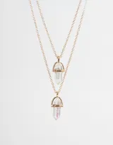 Set de dos collares dorados con dije de cristal facetado transparente con detalles iridiscentes.