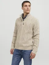 Sweater de punto color beige con cuello alto, cierre parcial con tres botones de madera y diseño con patrón de rombos y trenzas.