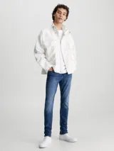 Jeans de denim elástico azul con efecto lavado, corte skinny, tiro bajo, cinco bolsillos y cierre con cremallera.