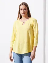 Blusa blanca de tejido labrado con cuello redondo, escote en V y aplique metálico.