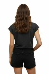 Remera negra de algodón con cuello redondo y mangas cortas. Presenta un estampado abstracto con apliques de strass dorados.