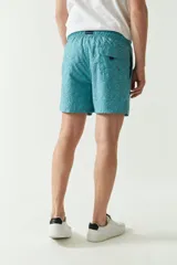 Short de baño celeste con estampado de hojas, cintura elástica con cordón ajustable, dos bolsillos laterales y uno trasero.