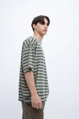 Remera verde con rayas horizontales azul marino, corte boxy y estampado con el número 1956 en el pecho.