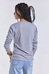 Remera gris de manga larga con cuello redondo y corte clásico.