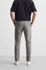 Pantalón negro de corte slim fit, confeccionado en tejido elástico. Cuenta con cintura elástica, bolsillos frontales y traseros de vivo. Cierre frontal con cremallera y botón.