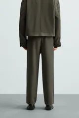 Pantalón verde oscuro de corte recto, con cintura elástica, bolsillos laterales y un bolsillo trasero. Cierre frontal con cremallera y botón.