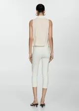 Blusa negra sin mangas con cuello camisero y cierre de lazos en la parte delantera.