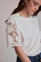 Remera blanca de algodón con mangas cortas de encaje floral.