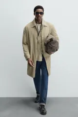 Gabardina color beige de corte recto, con cuello solapa, cierre frontal con botones, bolsillos laterales y puños ajustables con trabilla.