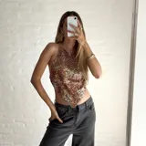 Top corto con estampado abstracto en tonos marrones, blancos y amarillos. Diseño tipo pañuelo con tirantes finos que se atan en la espalda y el cuello.