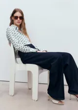 Camisa de manga larga con puños abotonados, cuello camisero y cierre frontal con botones ocultos. Presenta un estampado geométrico en tonos azul y verde sobre fondo blanco, y corte recto.