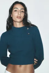 Sweater color crudo de tejido de punto acanalado, con cuello solapa abotonado y mangas largas abullonadas.