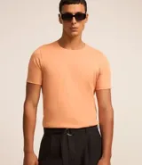 Remera slim de manga corta color salmón, de punto medio, sin estampado y cuello redondo.