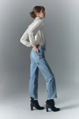 Pantalón de jean de tiro alto, denim azul rígido con lavado localizado, apliques de brillos, pierna recta y ruedo desflecado.