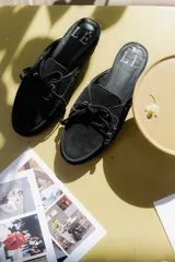 Mocasines tipo mule color beige, con detalle de cordones y ojales metálicos.