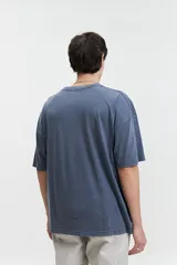 Remera azul de manga corta con cuello redondo, corte holgado y logo bordado en el pecho.