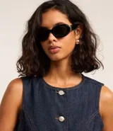 Chaleco femenino confeccionado en jeans, sin mangas, cinturado, con botones y bolsillos. De corte alargado y cuello redondo.