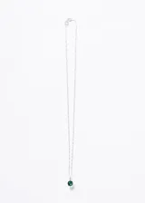 Collar con cadena de plata 925, con dije colgante que presenta una piedra central redonda de color verde esmeralda engastada en cuatro garras, flanqueada por circonias cúbicas incrustadas en la barra superior.