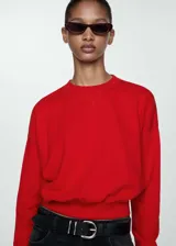 Buzo rojo de algodón con cuello redondo, mangas largas con puños elásticos y bajo con goma elástica.