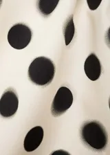 Minifalda color crema con estampado de lunares negros, de tejido satinado y corte recto.