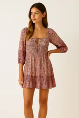 Vestido corto con estampado floral multicolor, escote cuadrado con lazo ajustable, mangas 3/4 abullonadas con elástico, corte evasé y frunces en el busto.