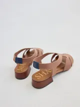 Sandalias bajas negras con tiras anchas de neopreno entrecruzadas en el empeine y talón descubierto. Plataforma de madera con letras grabadas en la plantilla.