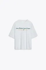 Camiseta gris jaspeado de corte oversize, cuello redondo y manga corta. Estampado frontal con la frase "Santa Monica Sports League Los Angeles Est. 1974" en verde y dorado.