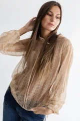 Camisa de encaje de tul bordado color beige, con cuello mao sin botones, abertura en el escote y lazo para atar. Corte amplio con tiras a los costados para fruncir la prenda o dejarla recta. Mangas amplias con detalle de tres alforzas profundas y terminación balloon.