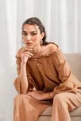 Blusa color marrón claro de lino con escote off-shoulder con volantes, mangas tres cuartos y cierre frontal con botones.