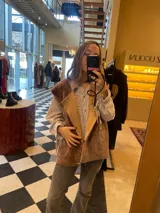 Chaleco de cuero genuino con textura de pelo en color marrón, diseño cruzado con cierre de botón lateral y cuello solapa.