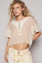 Remera color beige de manga corta con escote en bote y abotonado, corte oversize y estilo patchwork en dos telas.