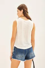 Musculosa blanca de encaje con cuello redondo.
