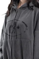 Campera gris de algodón con cierre frontal, capucha y bolsillos tipo canguro. Tiene costuras a la vista, remaches y bordado.