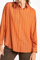 Camisa oversize color ladrillo con rayas verticales blancas y rosadas, de mangas largas y botones de madera.