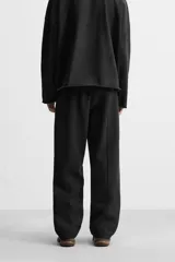 Pantalón wide fit confeccionado en tejido de algodón con interior en rizo, color negro. Cintura elástica ajustable con cordón interior, bolsillos frontales y detalle de bolsillo trasero de vivo. Perneras con costura frontal y efecto lavado.