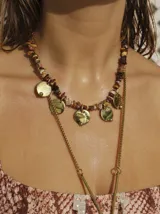 Collar corto con cuentas de piedras de colores y dijes de monedas de bronce. Collar largo con cadena dorada y dije de metal.