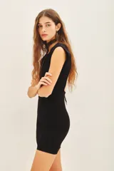 Vestido corto negro de punto, sin mangas, con cuello alto y espalda descubierta.