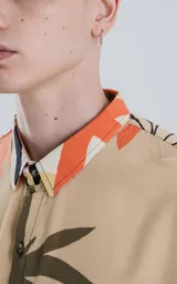 Camisa de manga larga con estampado de hojas en tonos beige, naranja, negro y verde.